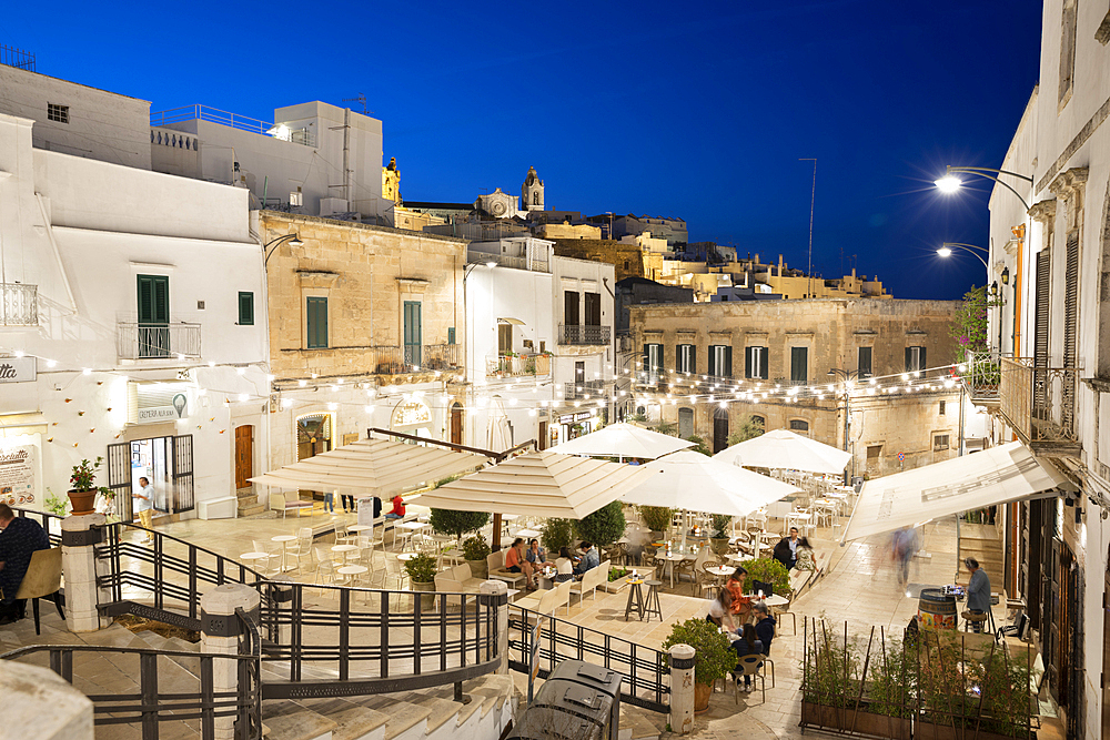 Restaurants lit up in the evening in Piazza della Liberta, Ostuni, Brindisi province, Puglia, Italy, Europe