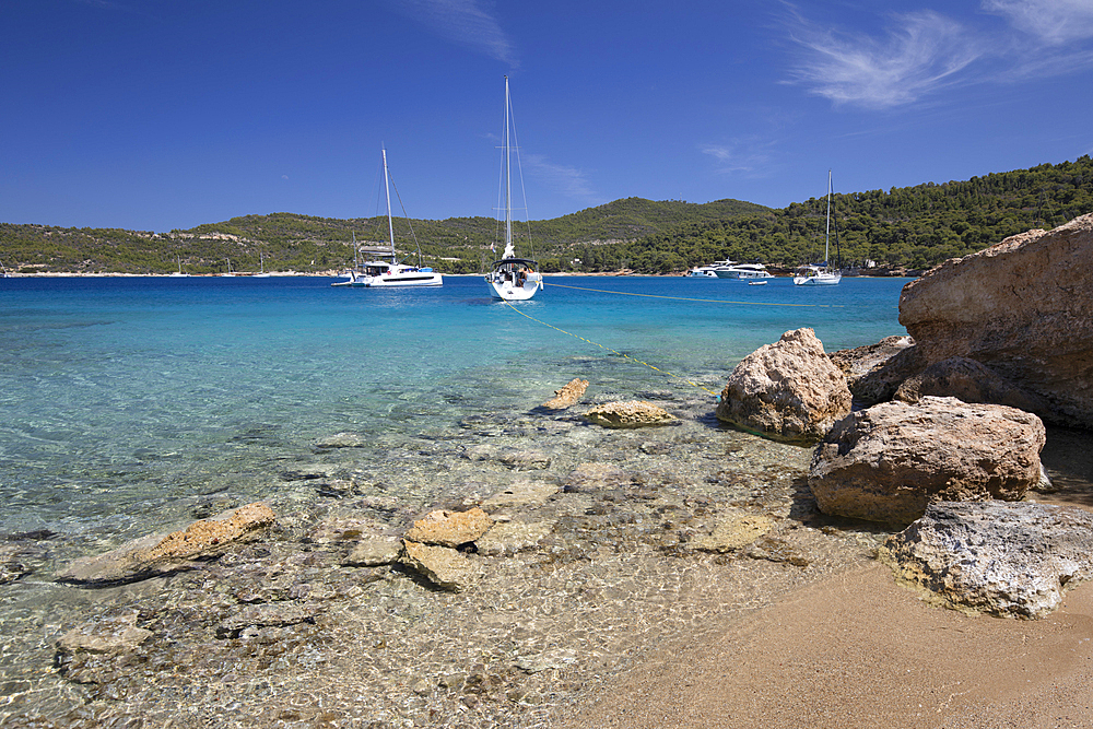 Paralia Zogerias beach with crystal clear blue water and yachts, Spetses, Saronic Islands, Greek Islands, Greece, Europe