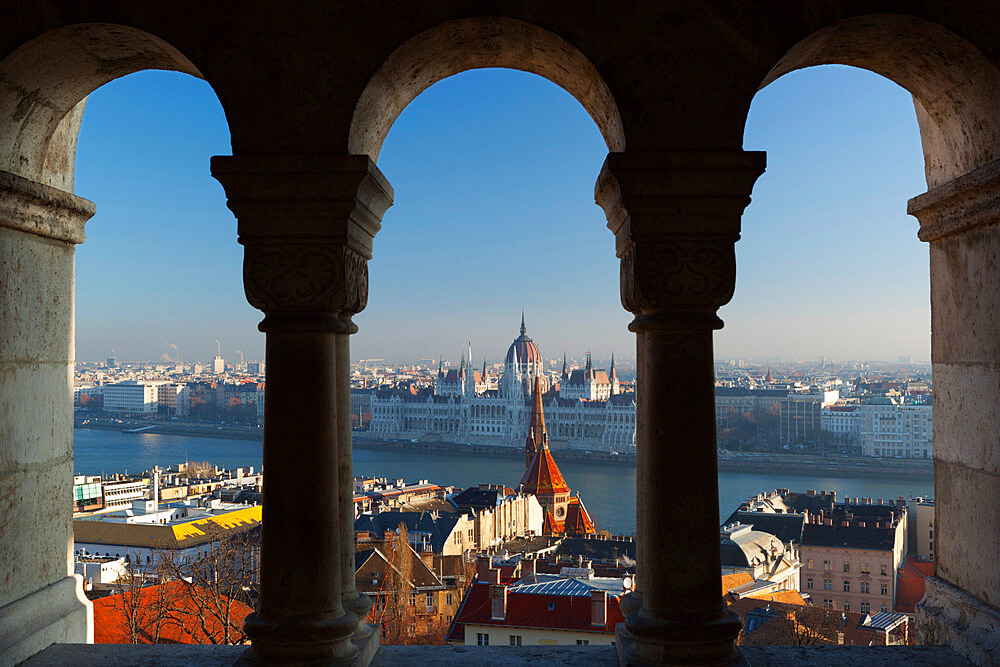 Parliament (Orszaghaz) and River Danube through arches of Fishermen's Bastion (Halaszbastya), UNESCO World Heritage Site, Buda, Budapest, Hungary, Europe