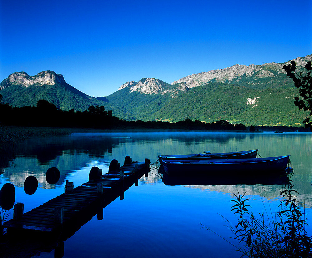 Silhouette of pier and rowing boats, Lake Annecy, Rhone Alpes, France, Europe