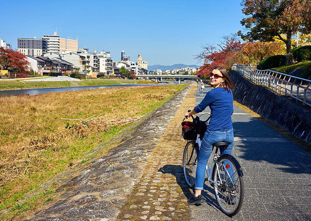 Cycling along the bank of the Kamo River in autumn, Kyoto, Japan, Asia