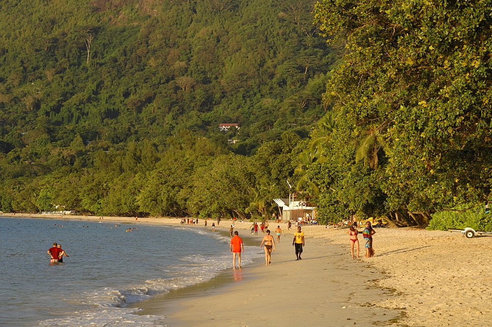 People walking along Beau Vallon beach, early evening light, Mahe, Seychelles, Indian Ocean