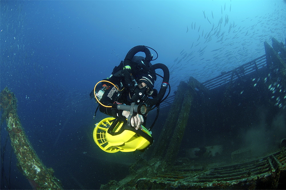 Mixed gas rebreather diver using scooter for mobility inside wreck.  Red Sea.