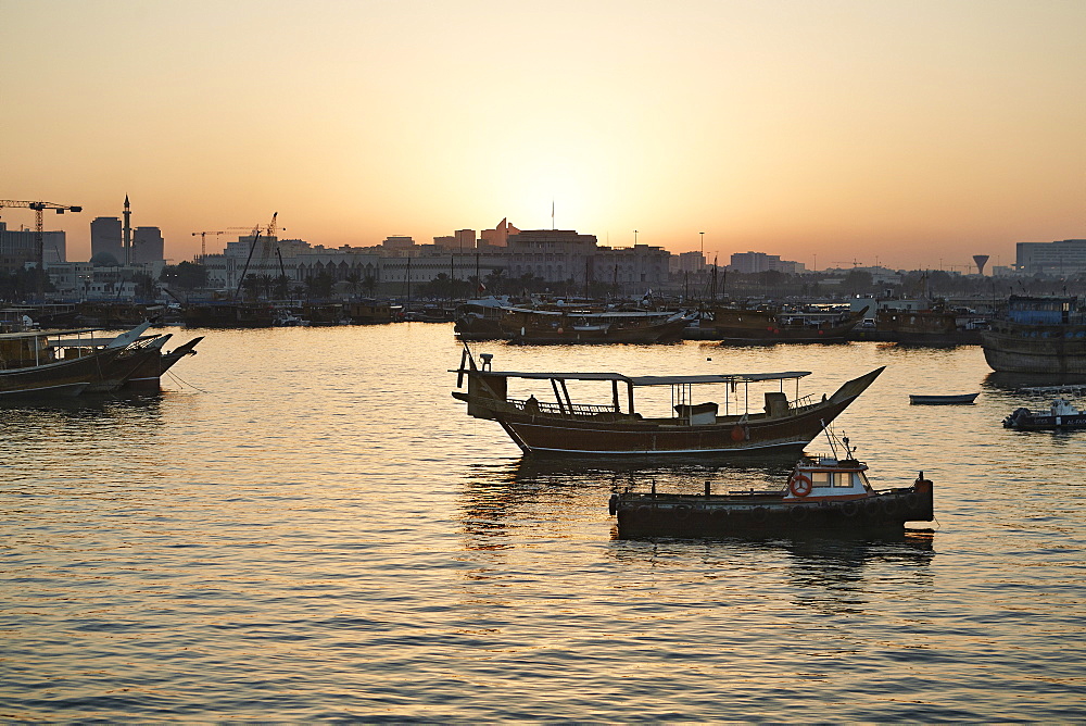 View from the Museum of Islamic Arts towards the old part of Doha and the dhows moored in the Harbour, at sunset, Doha, Qatar, Middle East