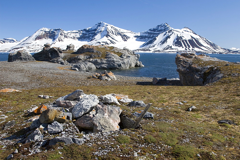 A view of the towering cliff and glacier in Hornsund (Horn Sound) on the southwestern side of Spitsbergen Island in the Svalbard Archipelago, Barents Sea, Norway. Shown here is a trappers gravesite.