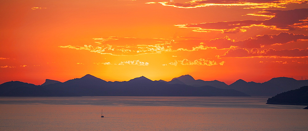 A lone fishing boat returns at dusk, with the island of Kolocep in the background, Dubrovnik, Croatia, Europe