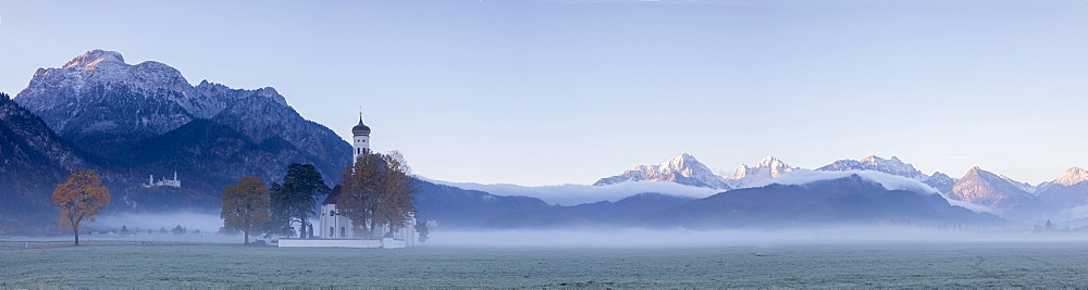 Panorama of St. Coloman Church surrounded by the autumn fog at sunrise, Schwangau, Bavaria, Germany, Europe