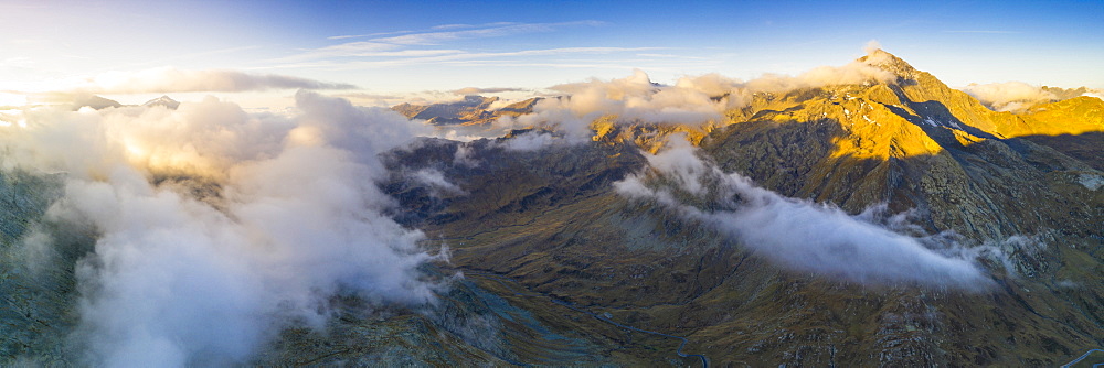 Aerial panoramic of sea of clouds over Pizzo Tambo and bends of the Spluga Pass road, Valle Spluga, Valtellina, Lombardy, Italy, Europe