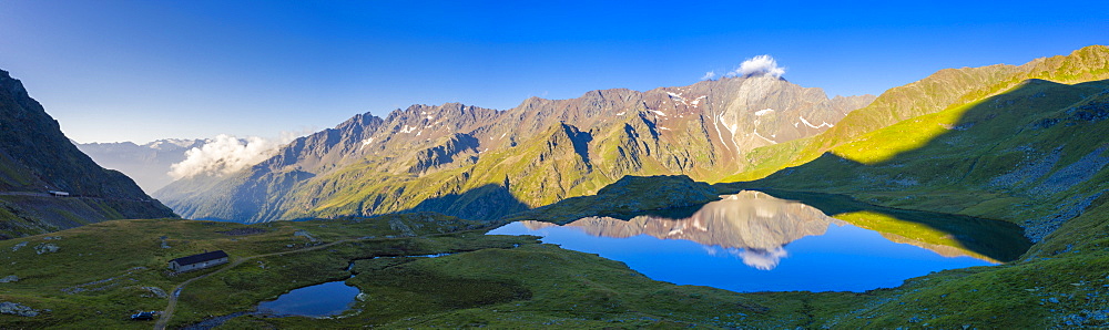 Aerial panoramic of Cima di Pietrarossa mirrored in Lago Nero at dawn, Gavia Pass, Valfurva, Valtellina, Lombardy, Italy, Europe