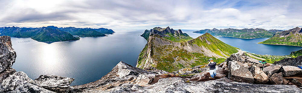 Man with camera photographing Hesten and Inste Kongen mountains standing on Segla peak, Senja island, Troms county, Norway, Scandinavia, Europe