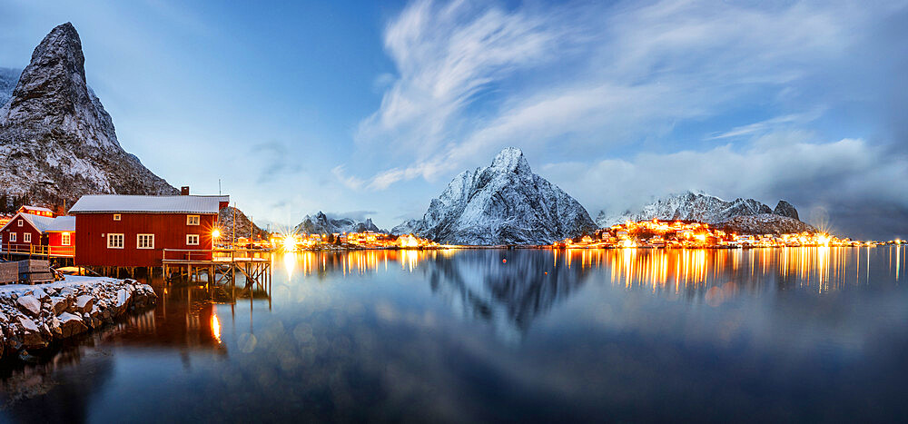 Olstind mount and traditional red fishermen's cabins mirrored in the cold sea at dusk, Reine, Nordland, Lofoten Islands, Norway, Scandinavia, Europe