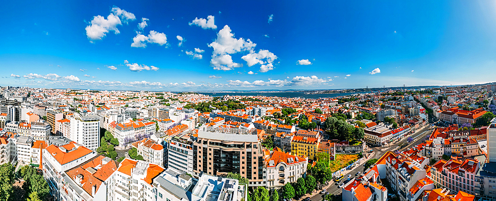 Aerial drone panoramic view of Lisbon's Baixa district on a sunny day looking south towards the Tagus with the 25 April Bridge visible, Lisbon, Portugal, Europe