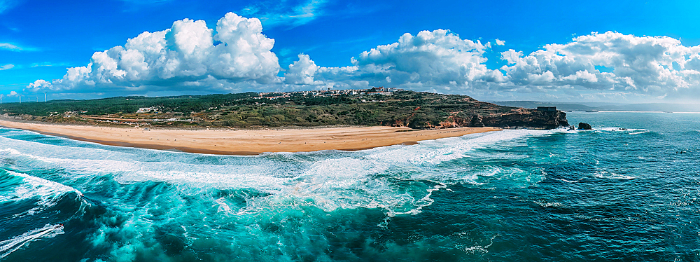 Aerial drone panoramic view of North Beach, with the iconic Sao Miguel Arcanjo lighthouse on the right, as well as the city of Nazare, Oeste, Estremadura, Portugal, Europe