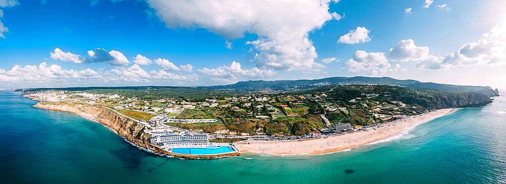 Panoramic view of Praia Grande is the largest beach on the Sintra coast, Portugal on an expanse of white sand that delights holidaymakers. The 100m swimming pool belonging to Arribas Hotel is the largest seawater pool in Europe