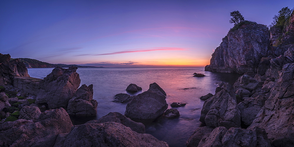 A colourful sunrise over Torbay with warm light on rocks, Babbacombe, Torquay, Devon, England, United Kingdom, Europe