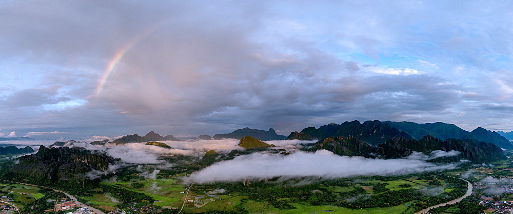 A panorama of a rainbow as dawn breaks over the mountains of Vang Vieng, Laos, Indochina, Southeast Asia, Asia