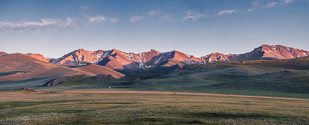 Panorama of sunset over snow-capped mountain range in the Song Kol lake area of Kyrgyzstan