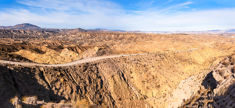 Panoramic view of the rugged desert landscapes in the Desierto de Gorafe with a dirt road leading through, Granada, Spain
