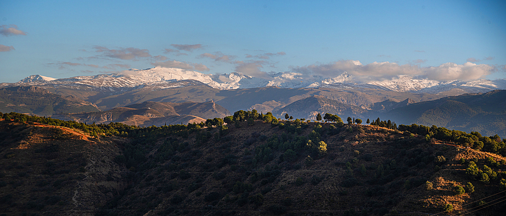 Sunset at the arid hill landscapes in front of the Snowy Sierra Nevada. View from Albaicin, Granada, Andalucia, Spain