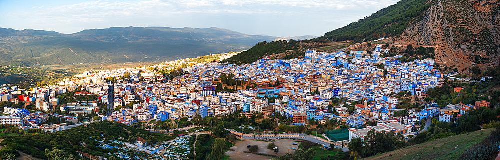 Sunrise over the skyline of the Chefchaouen Medina, Morocco. Warm light over blue houses in the Valley. Panoramic view showing the entire old town