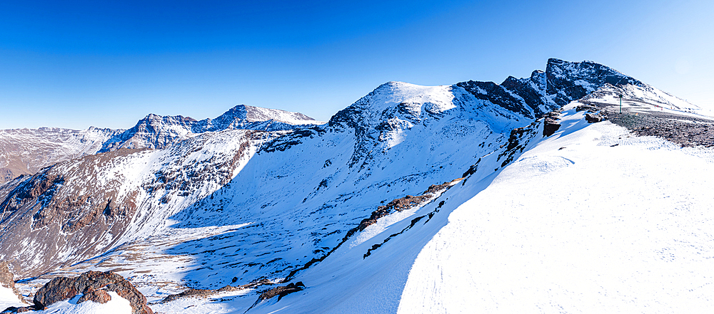 Snowy high altitude summits of the Spanish Sierra Nevada. Steep slopes of snow in front of Pico de la Veleta, Mulhacen and Alcazaba. Andalusia, Granada, Spain