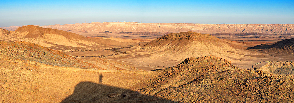 Panoramic view of Negev desert with shadow silhouette of a man on the mountain peak in sunrise