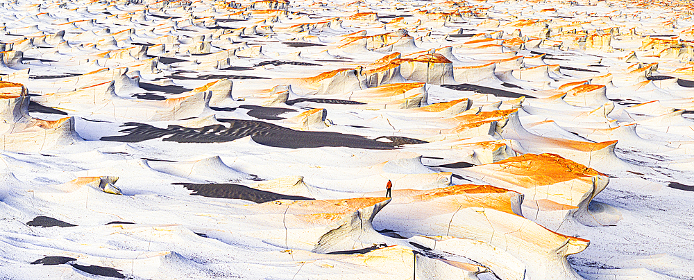 Aerial view of man watching sunrise over pumice fields standing on top of rocks, Campo de Piedra Pomez, El Penon, Argentina