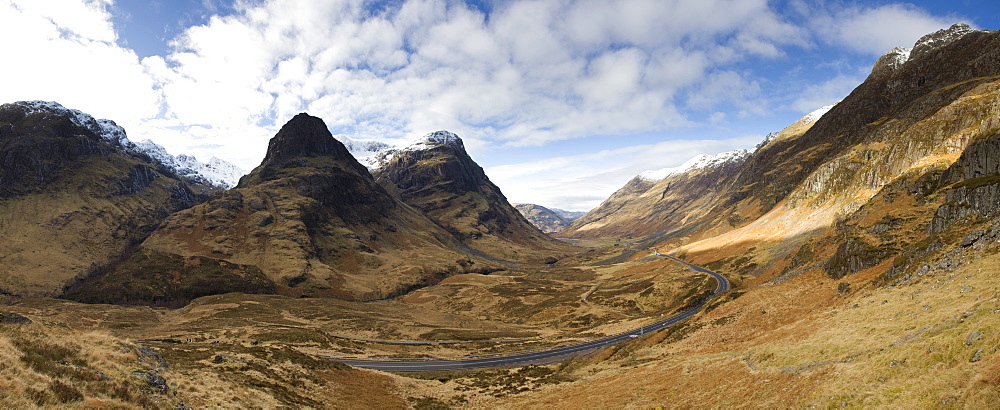 Panoramic view of Glencoe showing The Three Sisters of Glencoe mountains and the A82 trunk road winding down through the glen towards Glencoe Village, near Fort William, Highland, Scotland, United Kingdom, Europe