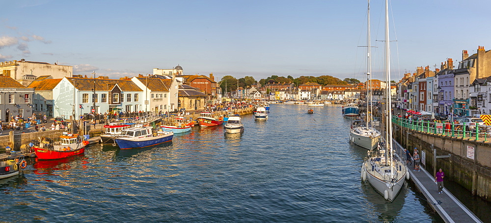 View of boats in the Old Harbour and quayside houses at sunset, Weymouth, Dorset, England, United Kingdom, Europe