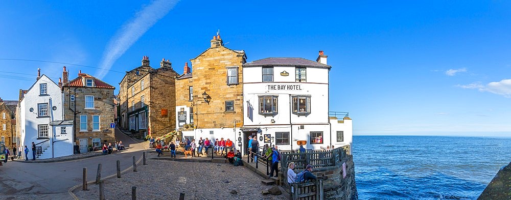 View of white washed Bay Hotel and visitors at harbour in Robin Hood's Bay, North Yorkshire, England, United Kingdom, Europe