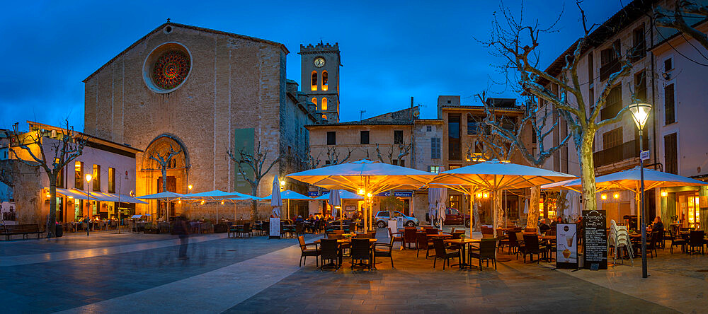 View of Santa Maria Church and people outside bar in Placa Mayor in the old town of Pollenca at dusk, Pollenca, Majorca, Balearic Islands, Spain, Mediterranean, Europe