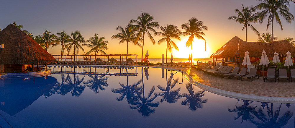 View of sunrise and palm tree reflections in hotel pool near Puerto Morelos, Caribbean Coast, Yucatan Peninsula, Mexico, North America