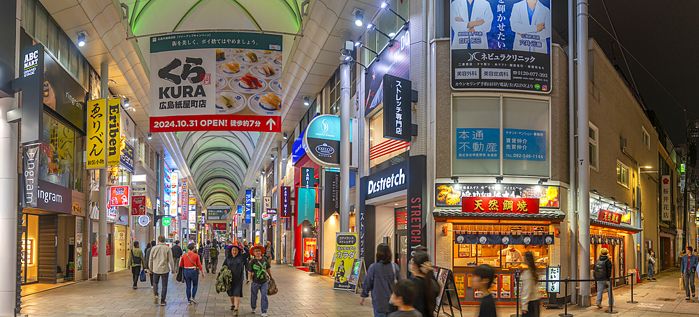 View of colourful shops and restaurants in shopping arcade at night, Hiroshima, Honshu, Japan