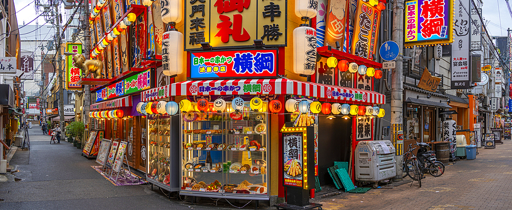 View of colourful facades of shops and restaurants in Dotonbori, vibrant entertainment district near the river, Osaka, Honshu, Japan