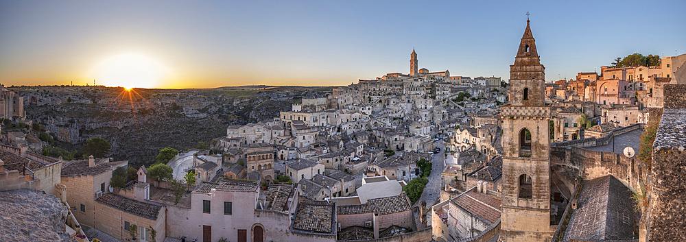 Sun rising over the canyon and Sassi di Matera old town with the campanile of the church of Saint Peter Barisano, Matera, Basilicata, Italy, Europe