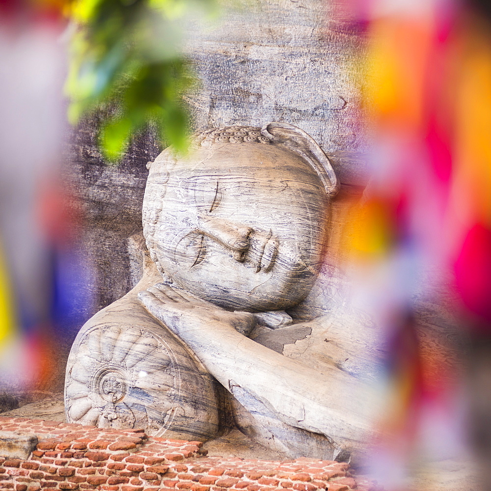 Buddhist prayer flags and reclining Buddha in Nirvana at Gal Vihara Rock Temple, Polonnaruwa, UNESCO World Heritage Site, Sri Lanka, Asia