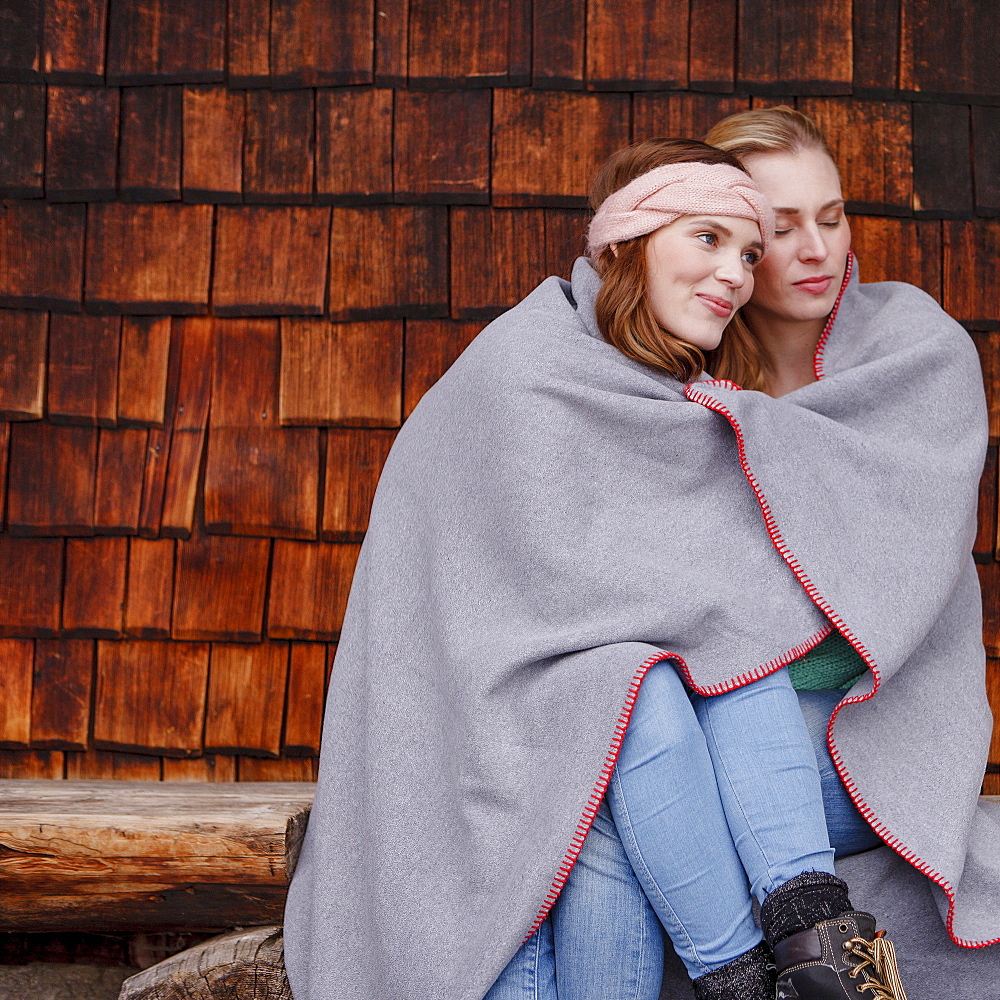 Two young women wrapped in a blanket, Spitzingsee, Upper Bavaria, Germany