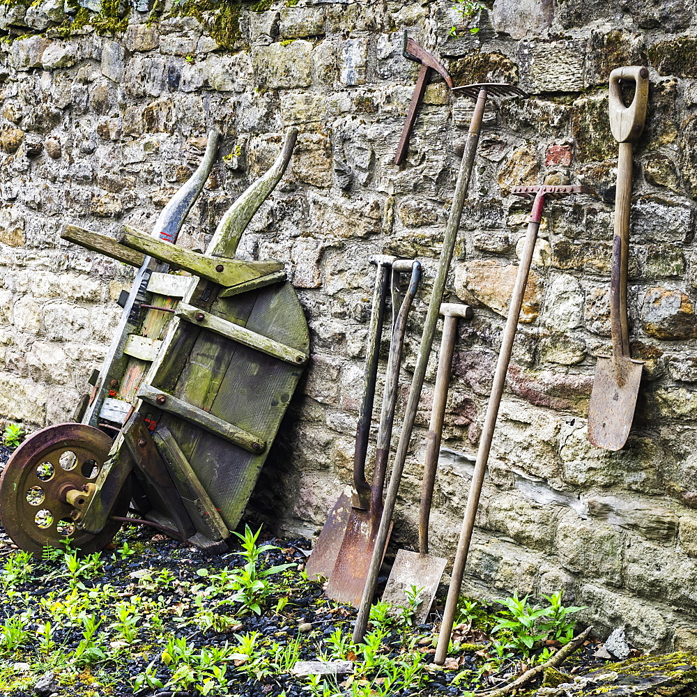 Old garden tools leaning up against a weathered stone wall, Open Air Museum, England