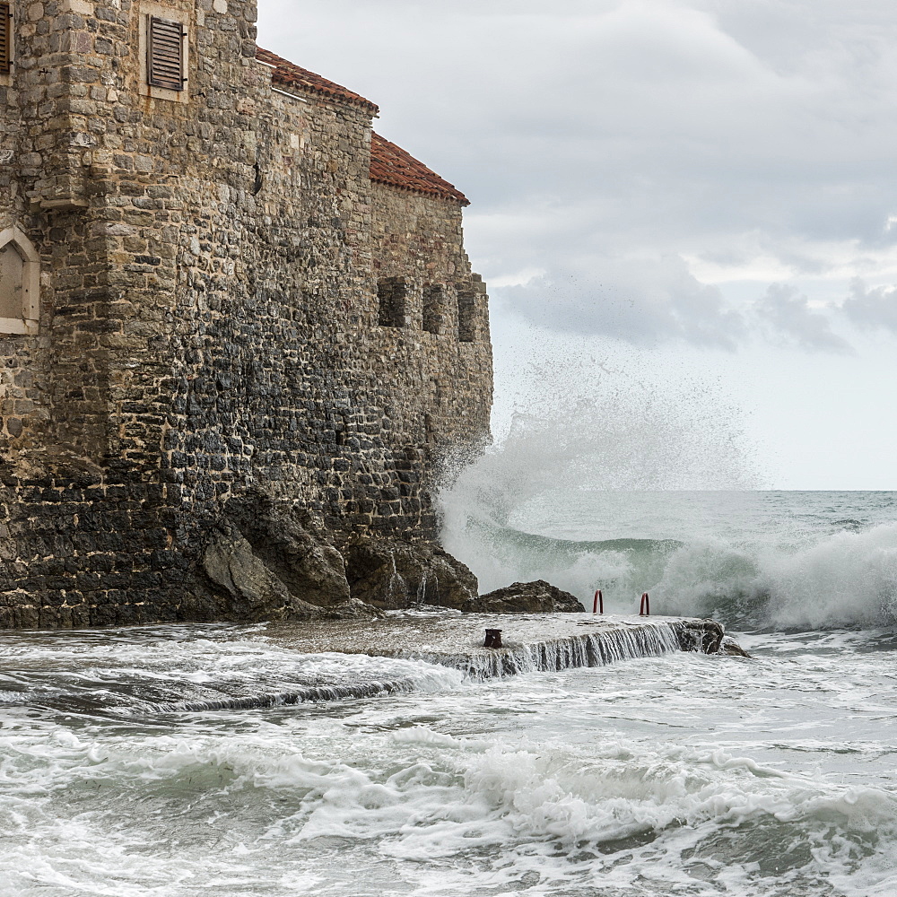 Waves crashing and splashing against the old stone walls along the coast of Budva, Budva, Opstina Budva, Montenegro