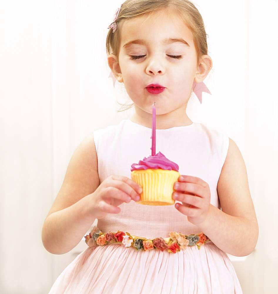 Young girl holding a birthday cupcake