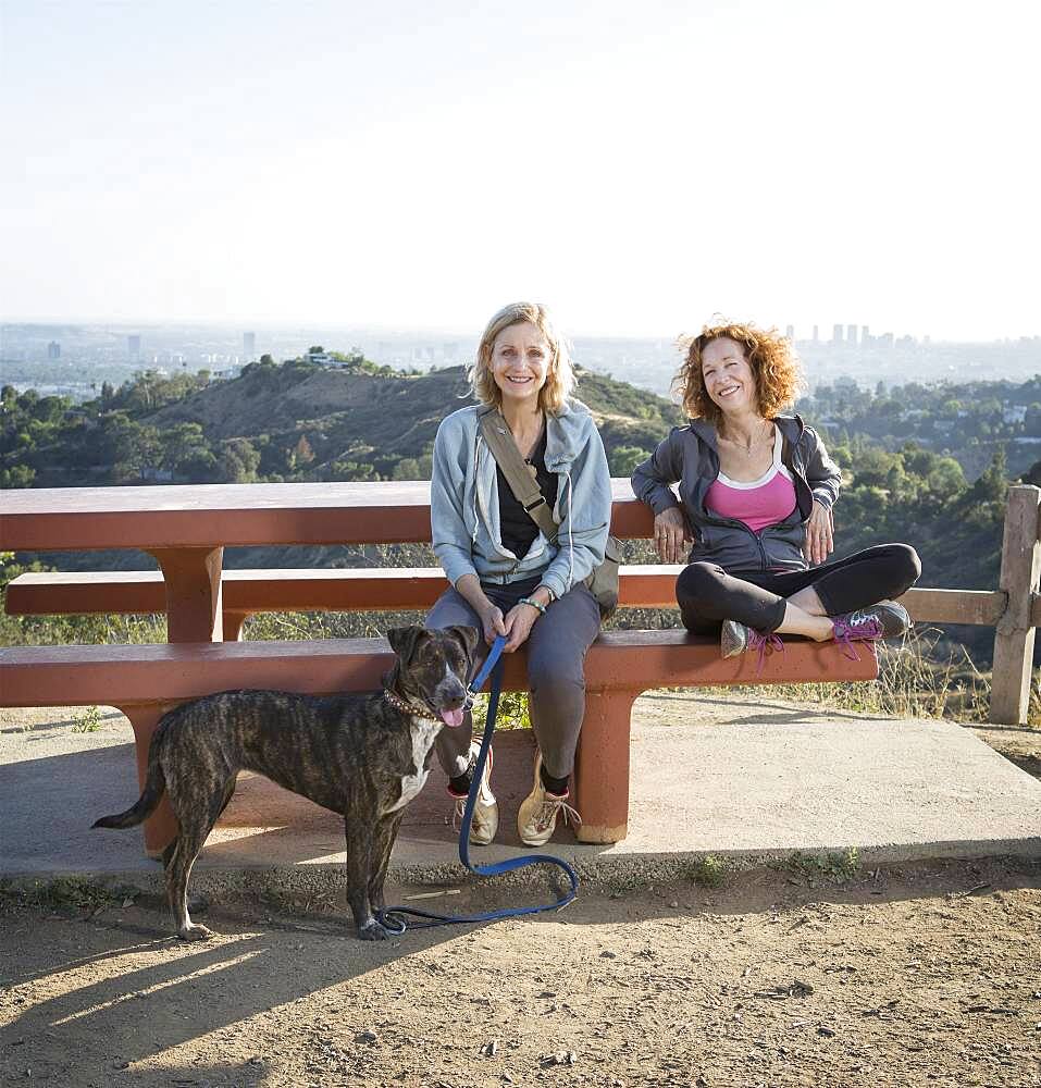 Caucasian women sitting with dog on hilltop