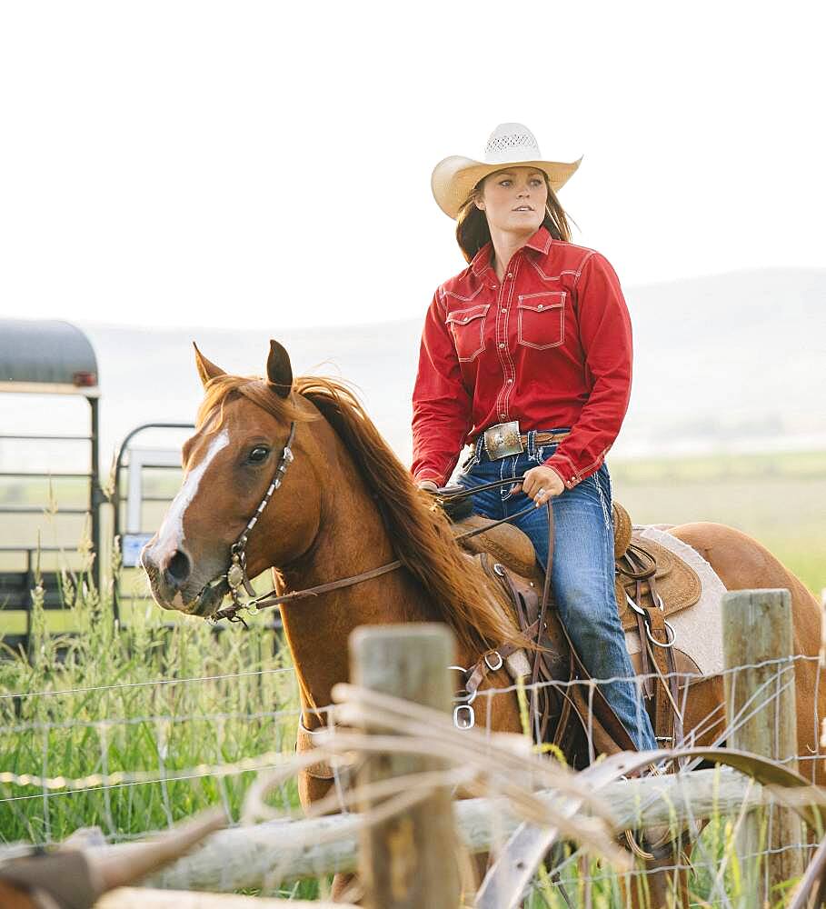 Caucasian cowgirl riding horse on ranch