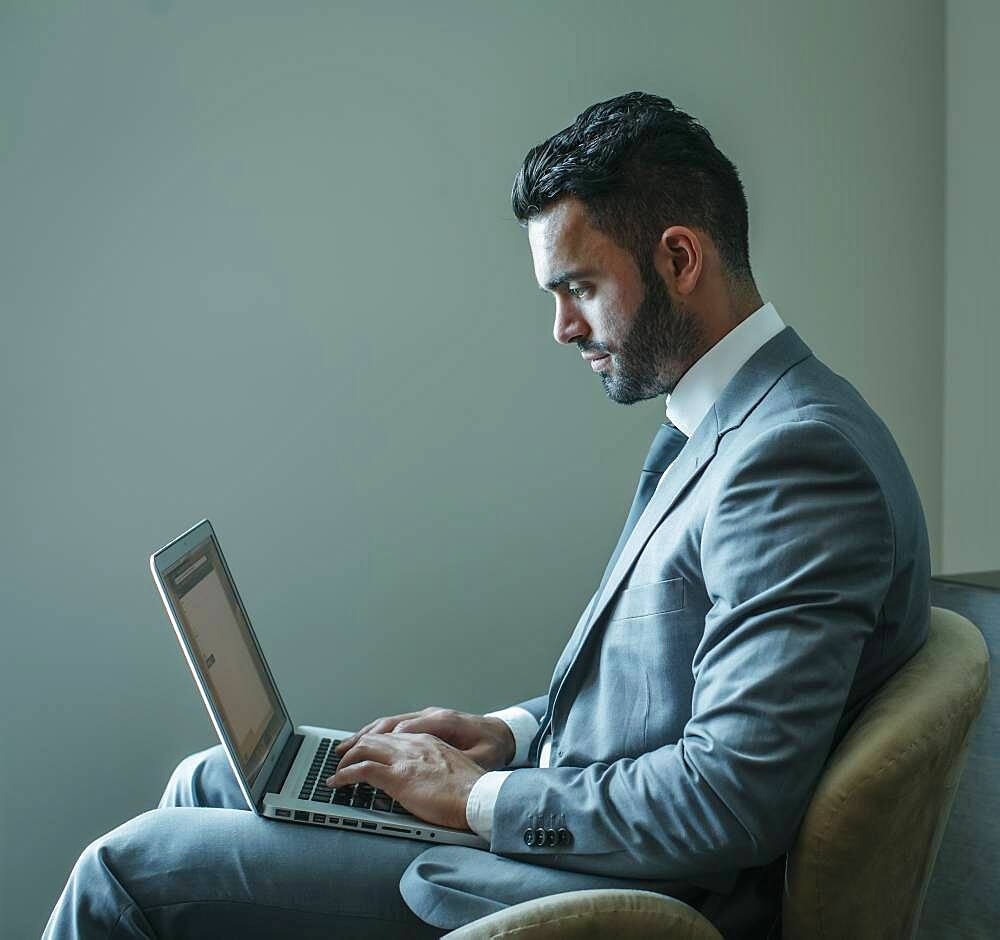 Businessman using laptop in armchair