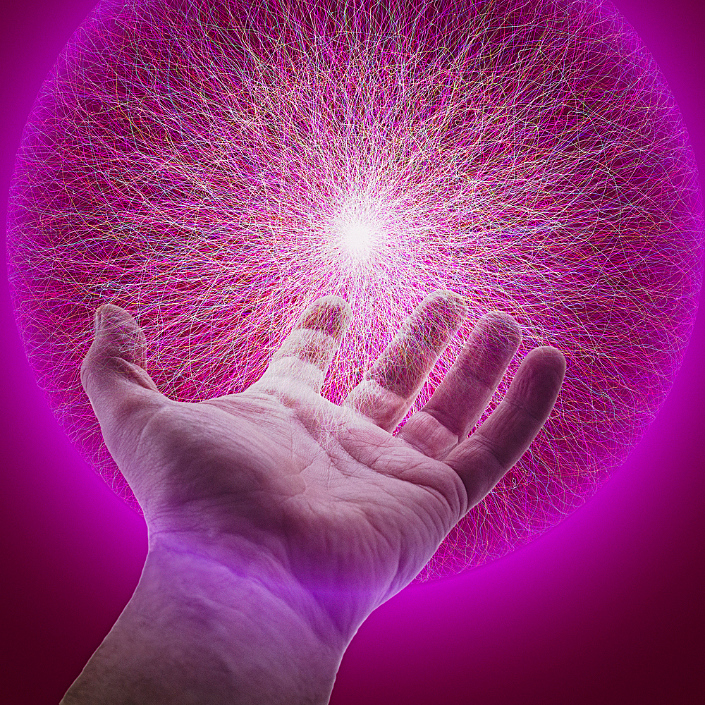 Hand of Caucasian man holding glowing sphere of purple energy