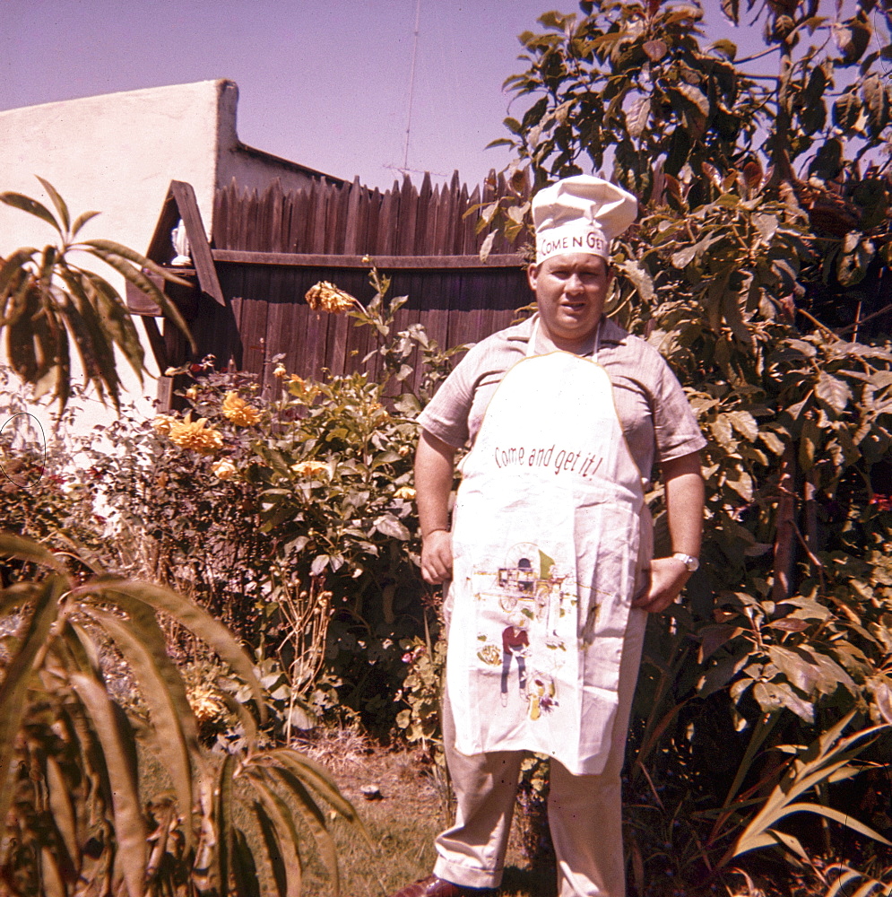 Caucasian man standing in yard wearing chef hat and apron