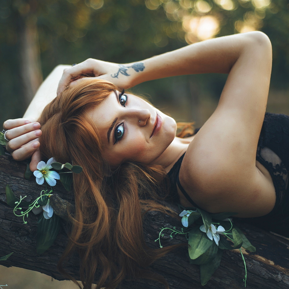 Smiling Caucasian woman laying on tree branch