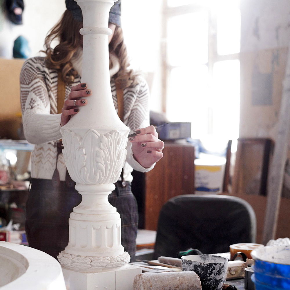 Caucasian artist sculpting with tool