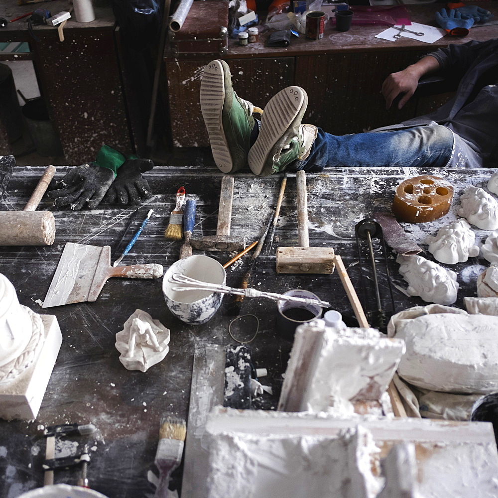 Feet of Caucasian sculptor on table