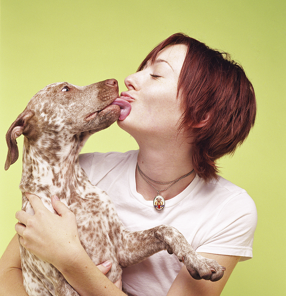 Dog licking face of woman