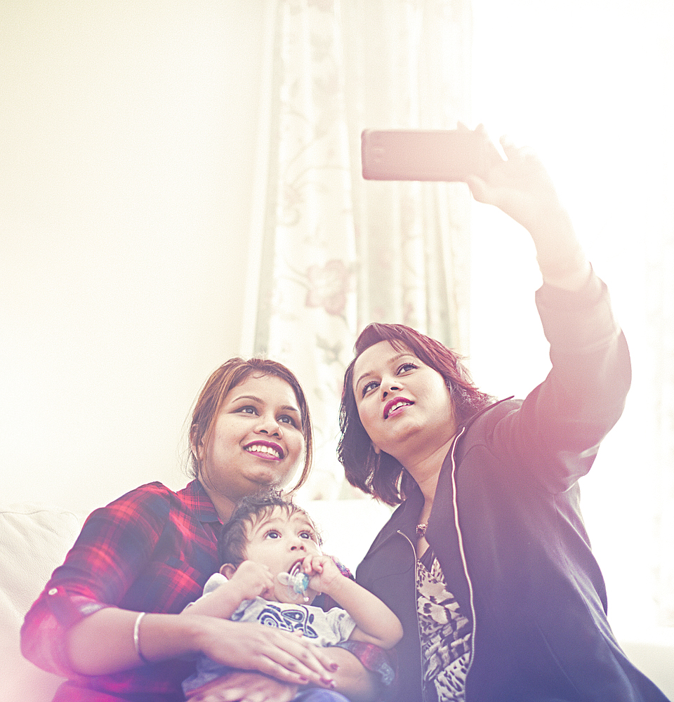 Indian women posing for cell phone selfie with baby boy